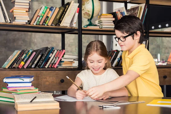 Crianças em idade escolar estudando na biblioteca — Fotografia de Stock