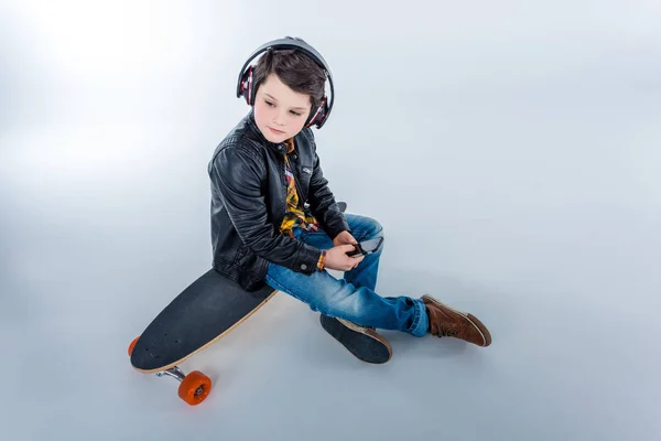 Хлопчик в навушниках зі скейтбордом — стокове фото