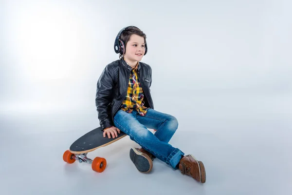 Niño en auriculares con monopatín - foto de stock