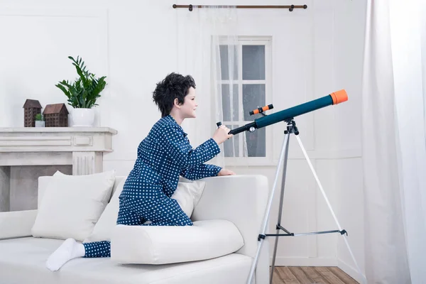 Niño mirando a través del telescopio - foto de stock