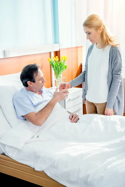 Wife giving glass of water to husband — Stock Photo