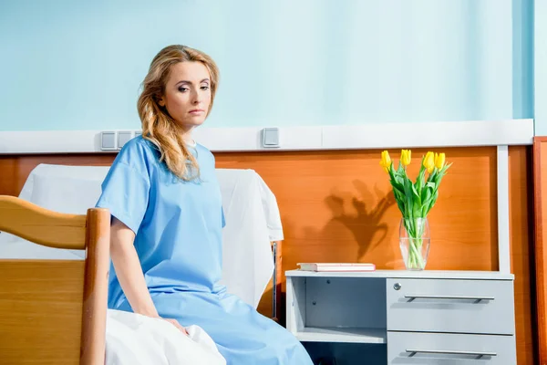 Mujer sentada en la cama del hospital - foto de stock