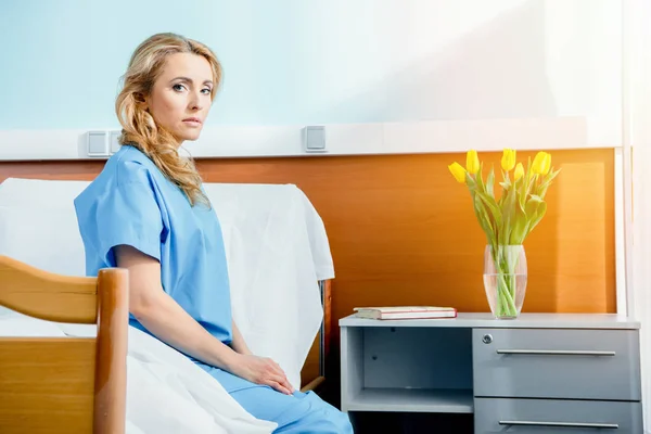Mujer sentada en la cama del hospital - foto de stock