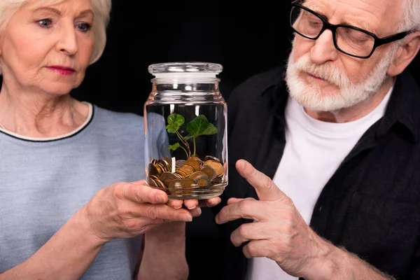 Pareja con monedas y planta en tarro - foto de stock