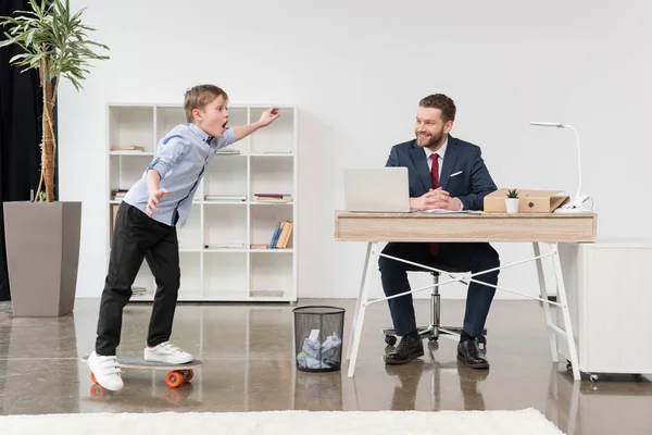 Boy skateboarding while father working — Stock Photo