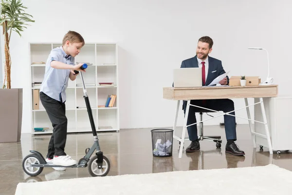Boy riding skooter at office — Stock Photo
