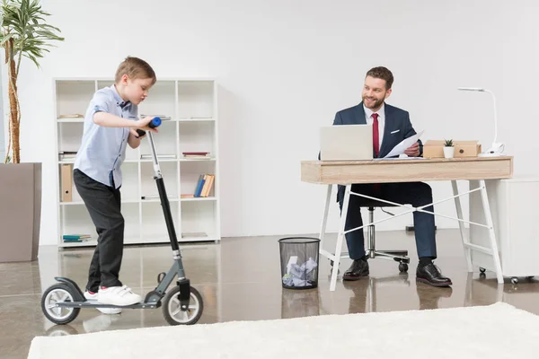 Garçon équitation skooter au bureau — Photo de stock