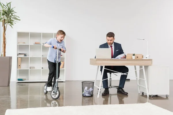 Мальчик катается на скутере в офисе — стоковое фото