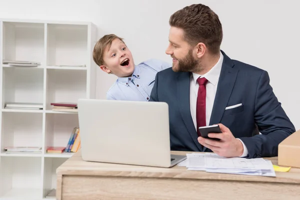 Niño travieso con su padre hombre de negocios - foto de stock