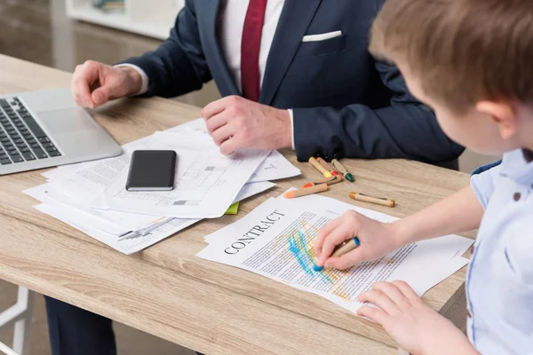 Empresário com filho desenhando em papéis de negócios — Fotografia de Stock