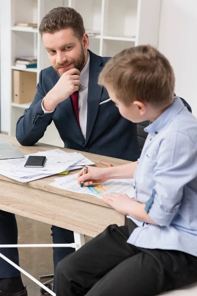 Empresário com filho desenhando em papéis de negócios — Fotografia de Stock