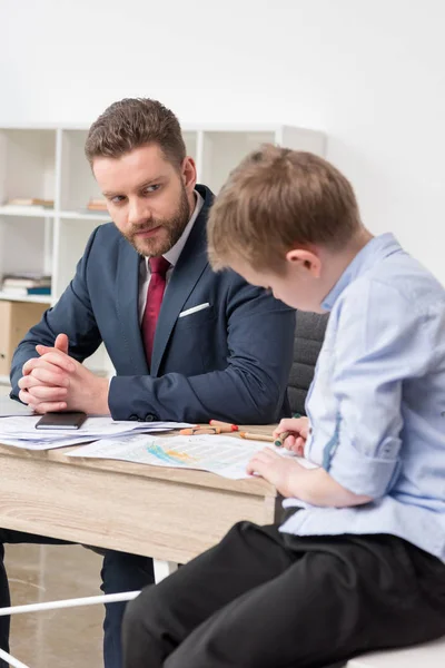 Бізнесмен з сином малює на бізнес-паперах — Stock Photo