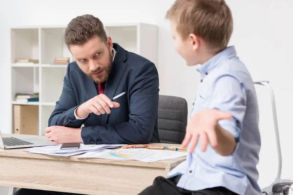 Empresario con hijo dibujando en papeles de negocios - foto de stock