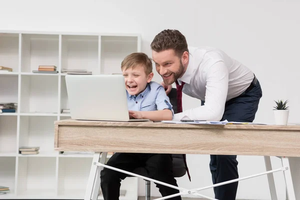 Businessman playing on laptop with son — Stock Photo