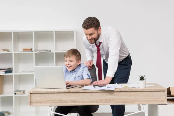 Empresario jugando en el ordenador portátil con hijo - foto de stock