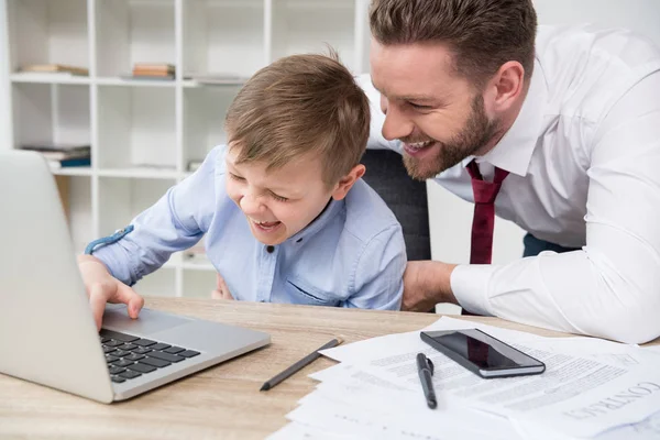 Empresario jugando en el ordenador portátil con hijo - foto de stock