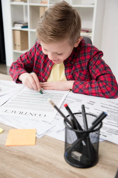 Неслухняний хлопчик малює на бізнес-паперах — стокове фото