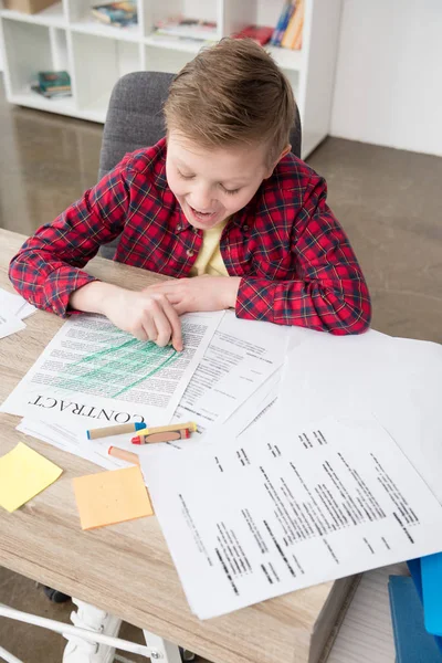 Niño travieso dibujando en papeles de negocios - foto de stock