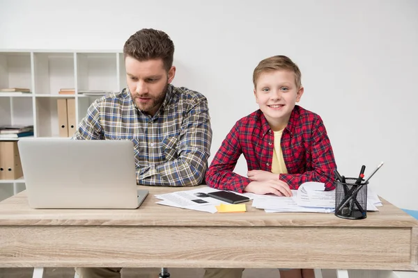 Freelancer trabalhando à mesa com filho — Fotografia de Stock