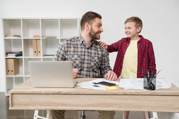 Freelancer working at table with son — Stock Photo