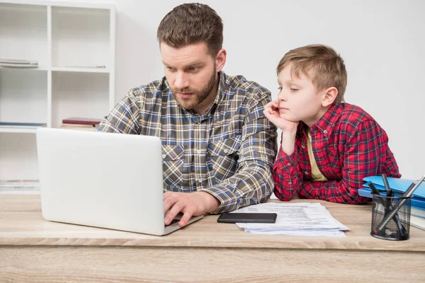 Freelancer usando laptop con hijo - foto de stock