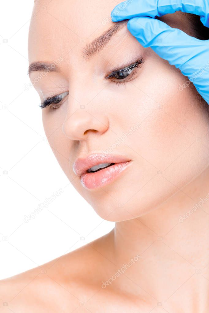 Cosmetologist examining eyebrow of patient