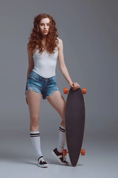 Jeune femme élégante avec skateboard — Photo