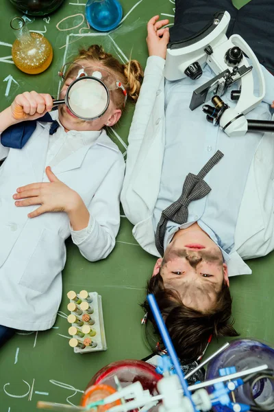 Kids in lab coats lying on chalkboard — Free Stock Photo