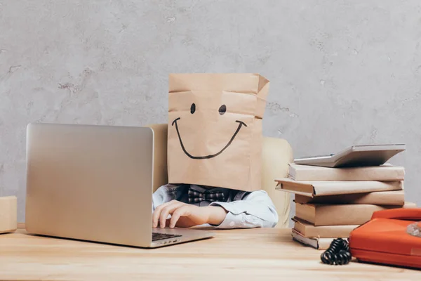 Ребенок с бумажным пакетом на голове с ноутбуком — стоковое фото