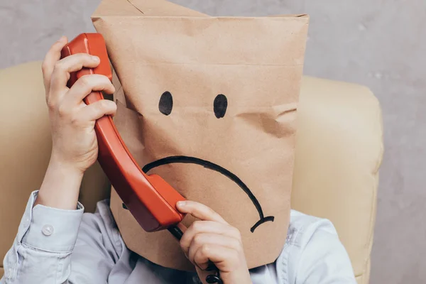 Child with paper bag on head with telephone — Stock Photo, Image