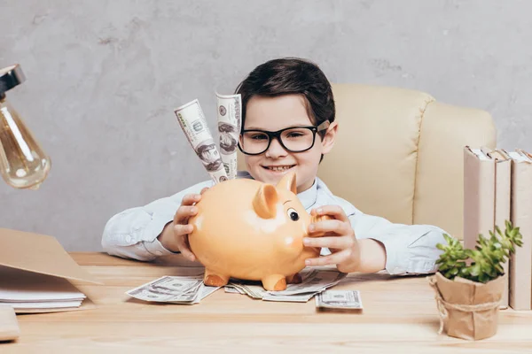 Kid with piggy bank at workplace — Stock Photo, Image