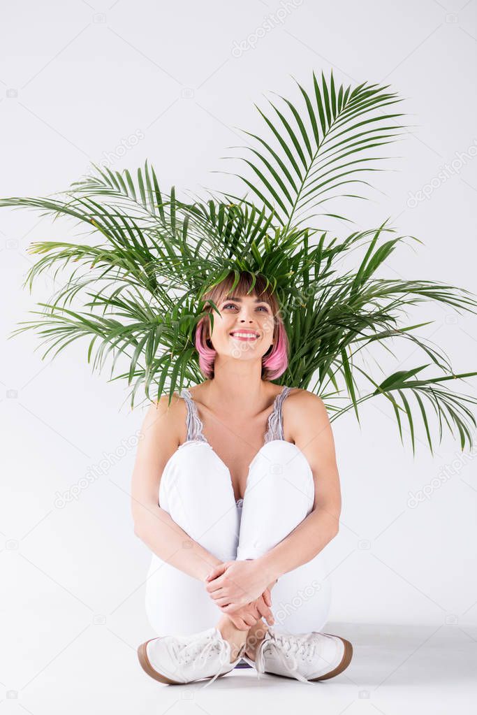 woman sitting under plant leaves