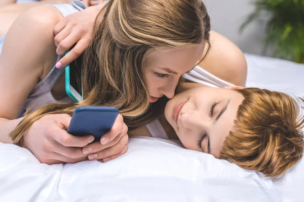 Junges Lesbisches Paar Kuschelt Bett Mit Smartphones — Stockfoto