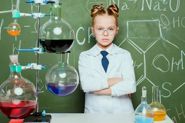 Chica en bata de laboratorio y gafas de protección - foto de stock