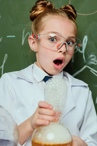 Chica en bata de laboratorio con frasco - foto de stock