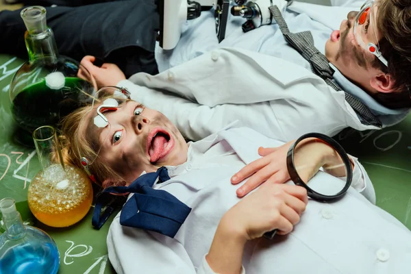 Kids in lab coats lying on chalkboard — Stock Photo