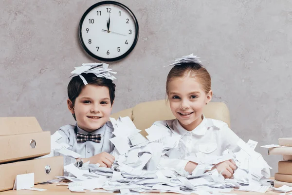 Niños y pila de papeles en el lugar de trabajo - foto de stock