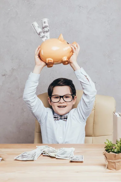 Niño con alcancía en el lugar de trabajo - foto de stock