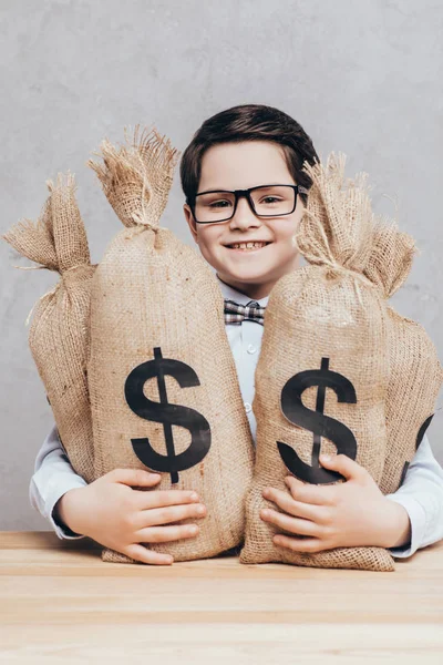 Маленький мальчик с мешками денег — стоковое фото
