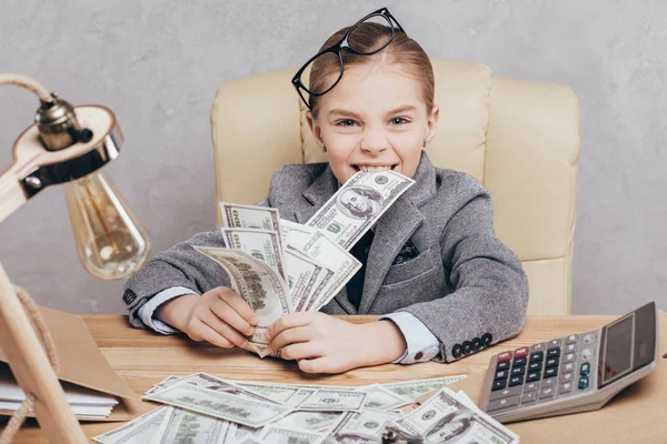 Bambino piccolo con soldi sul posto di lavoro — Foto stock
