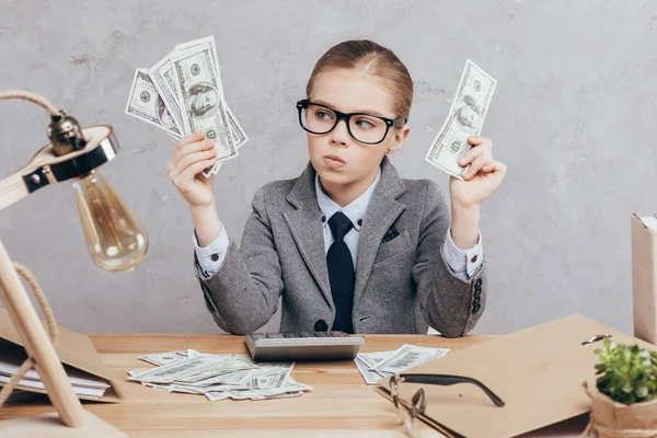 Nachdenkliches Kind hält Geld in den Händen — Stockfoto