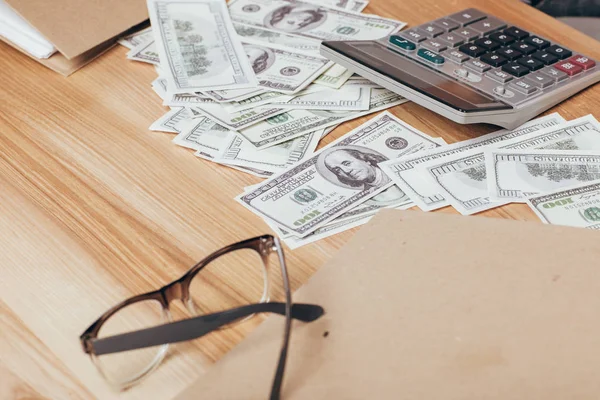 Dinero y calculadora en el lugar de trabajo - foto de stock