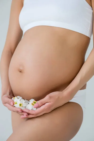 Belly of pregnant woman with flowers — Stock Photo