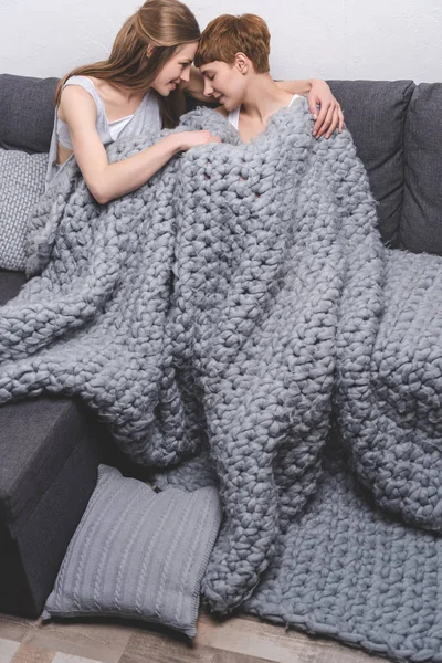 Giovane coppia lesbica coccole sotto coperta di lana lavorata a maglia — Foto stock
