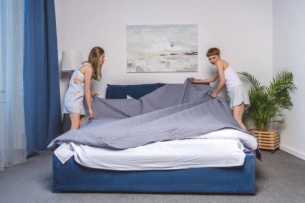 Lesbian couple covering up bed in morning — Stock Photo
