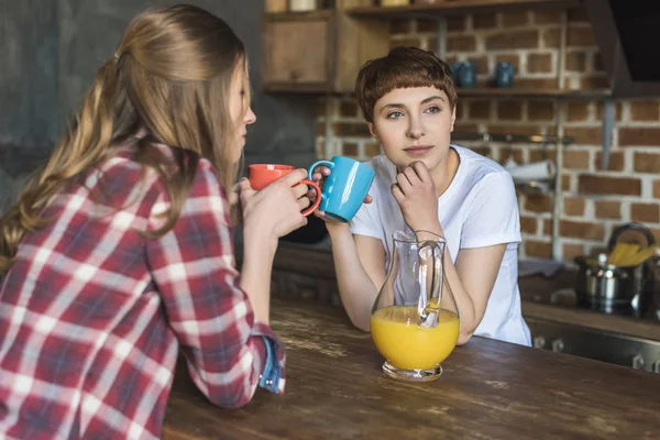 Привлекательные молодые женщины пьют кофе вместе на кухне — стоковое фото