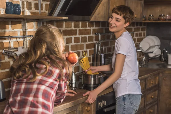 Giovane donna che parla con la sua ragazza mentre sta cucinando gli spaghetti — Foto stock