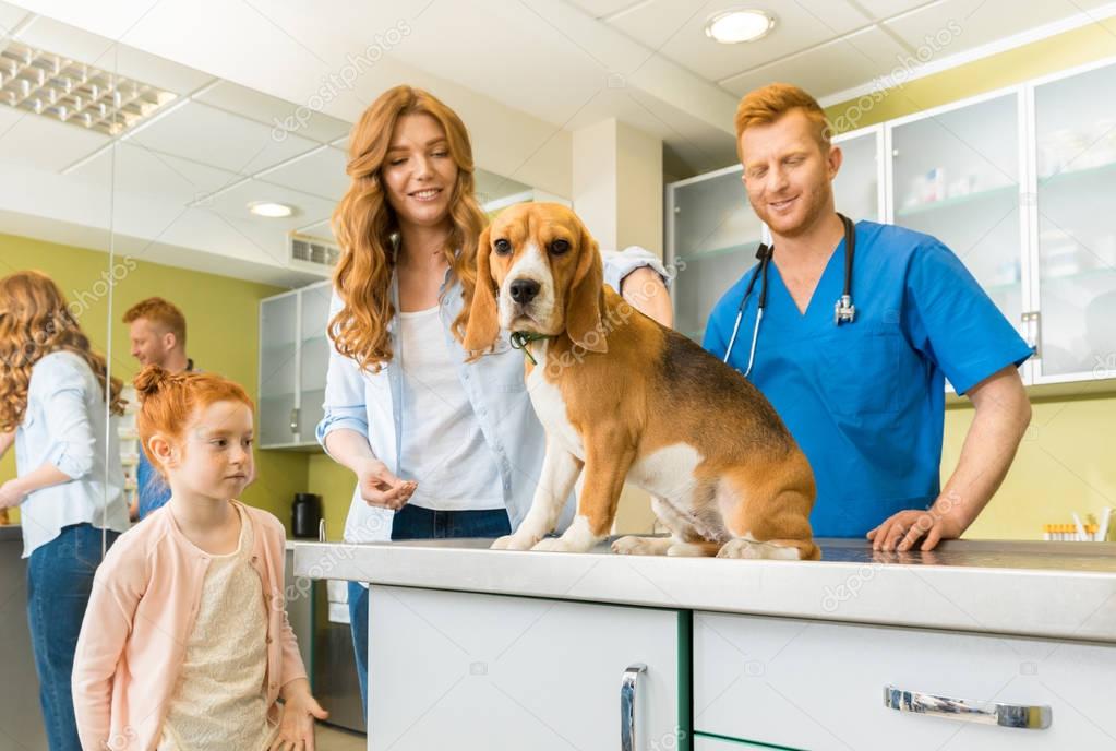 Woman, daughter with dog at veterinary doctor 