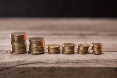 Stacks of coins on wooden tabletop clipart