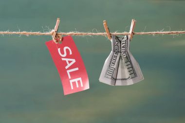 sale sign and dollar banknote on clothesline
